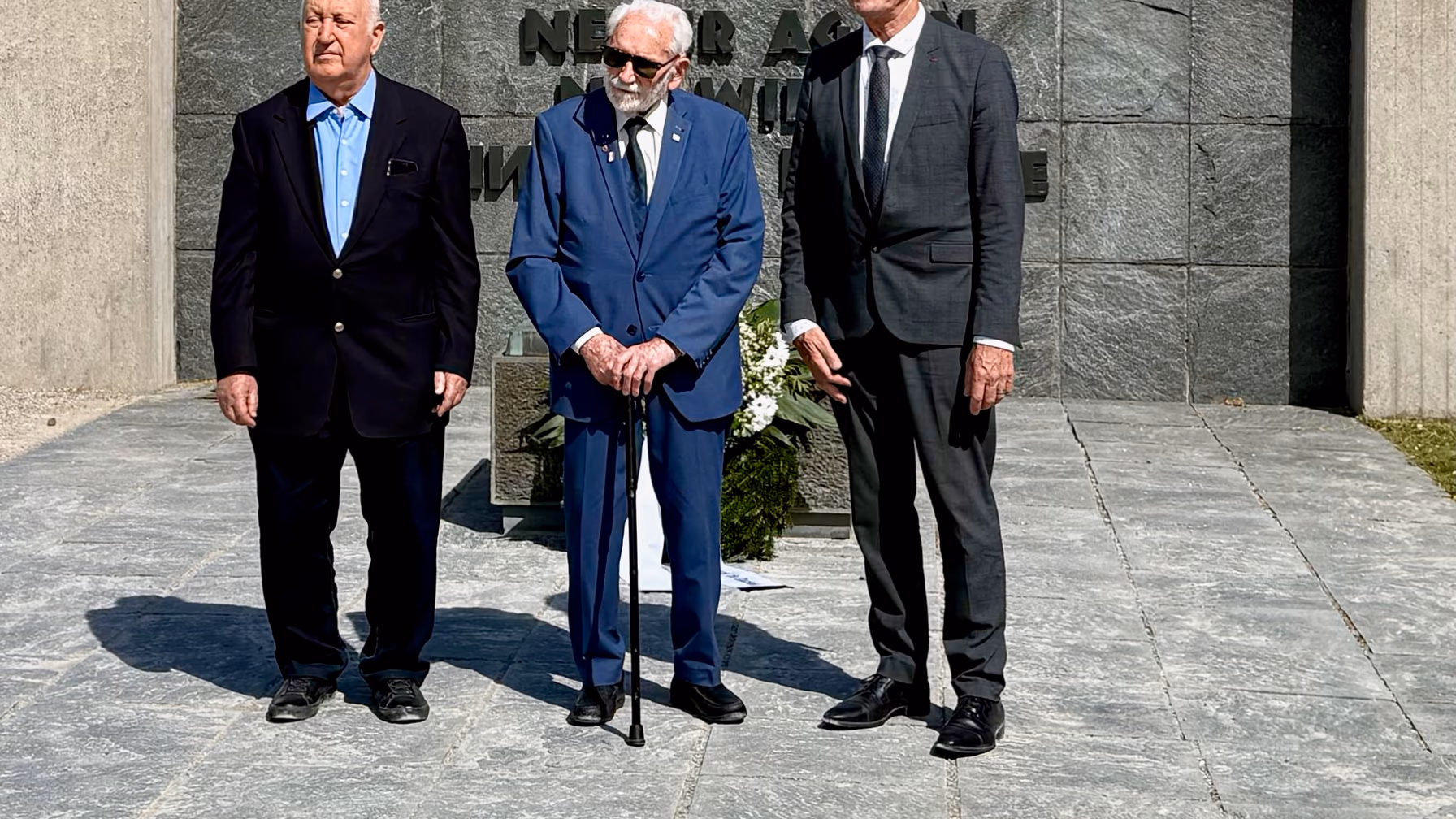 Kransnedleggelse foran «Aldri mer»-veggen ved det internasjonale monumentet i Dachau, mai 2026