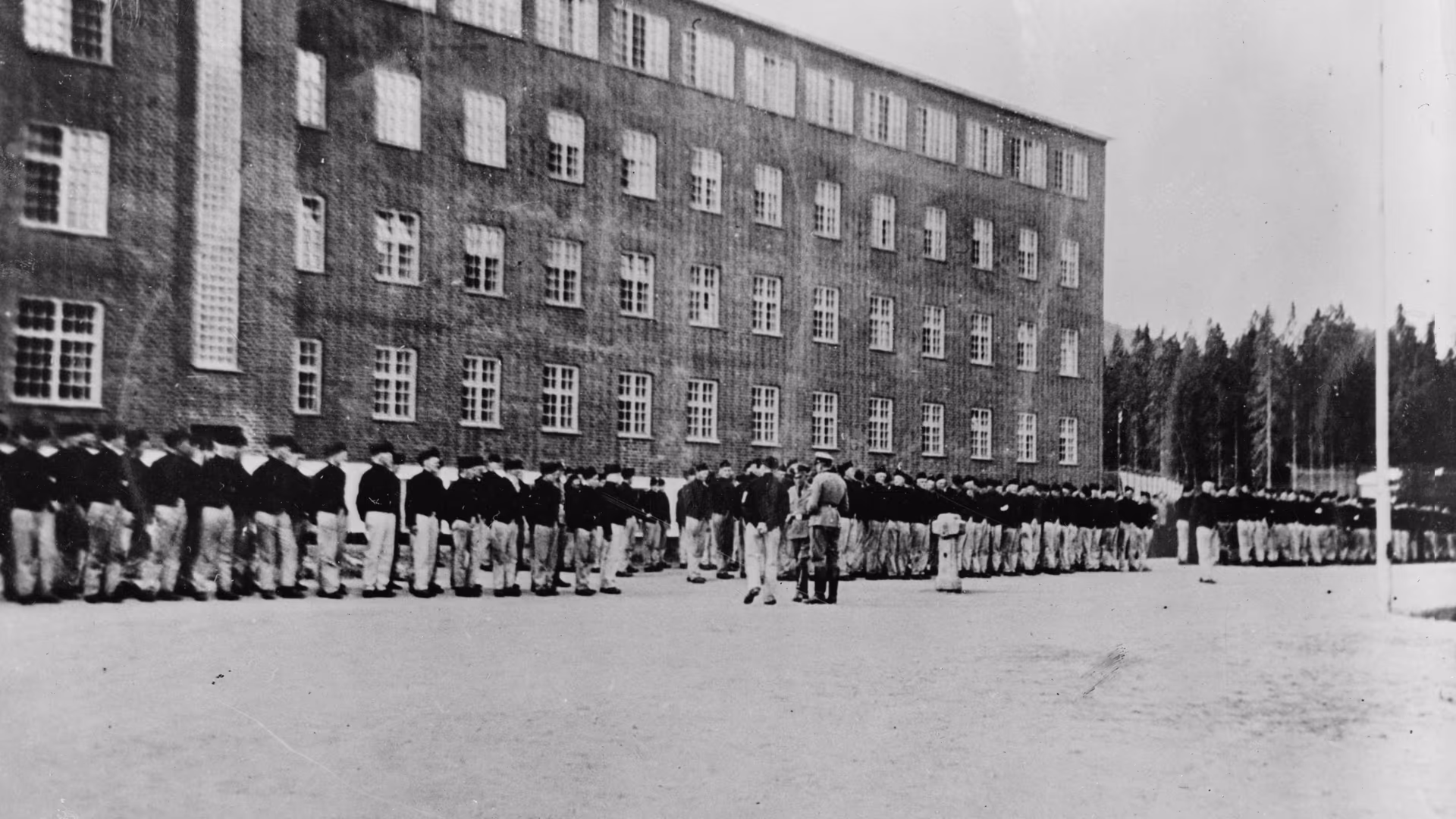 Fanger oppstilt til appell foran hovedbygningen på Grini fangeleir, 1941–43