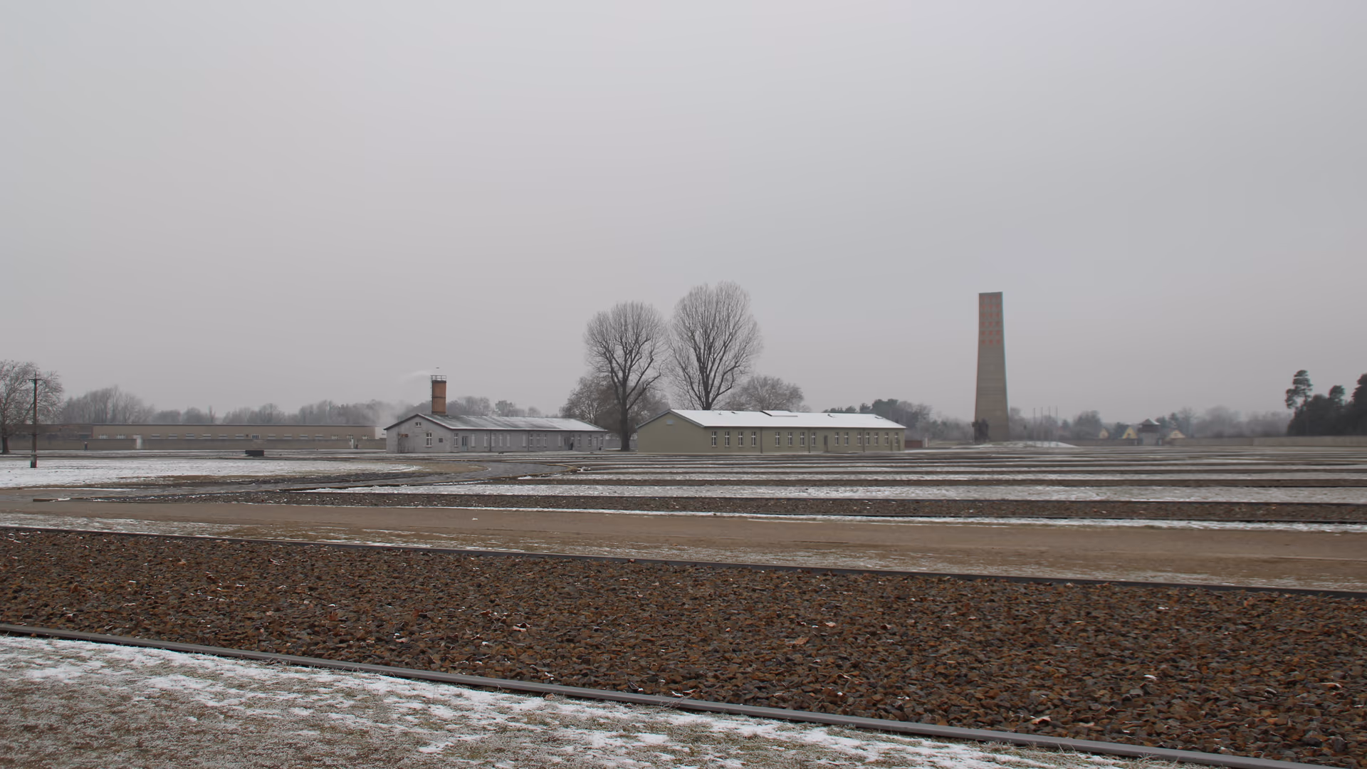 Snø over den tomme appellplassen på minnestedet Sachsenhausen, med krematorieskorsteinen i bakgrunnen